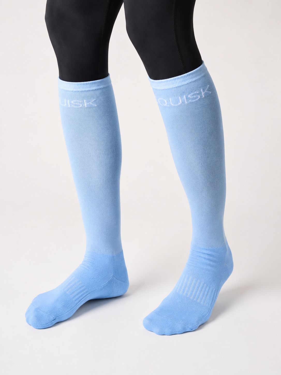 Light blue knee-high socks with 'EQUISK' branding worn by a person on a white background