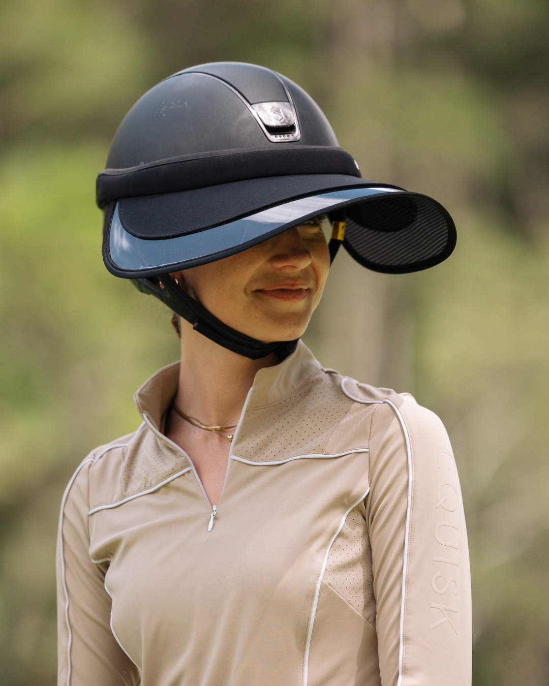Person wearing a black riding helmet with a visor outdoors